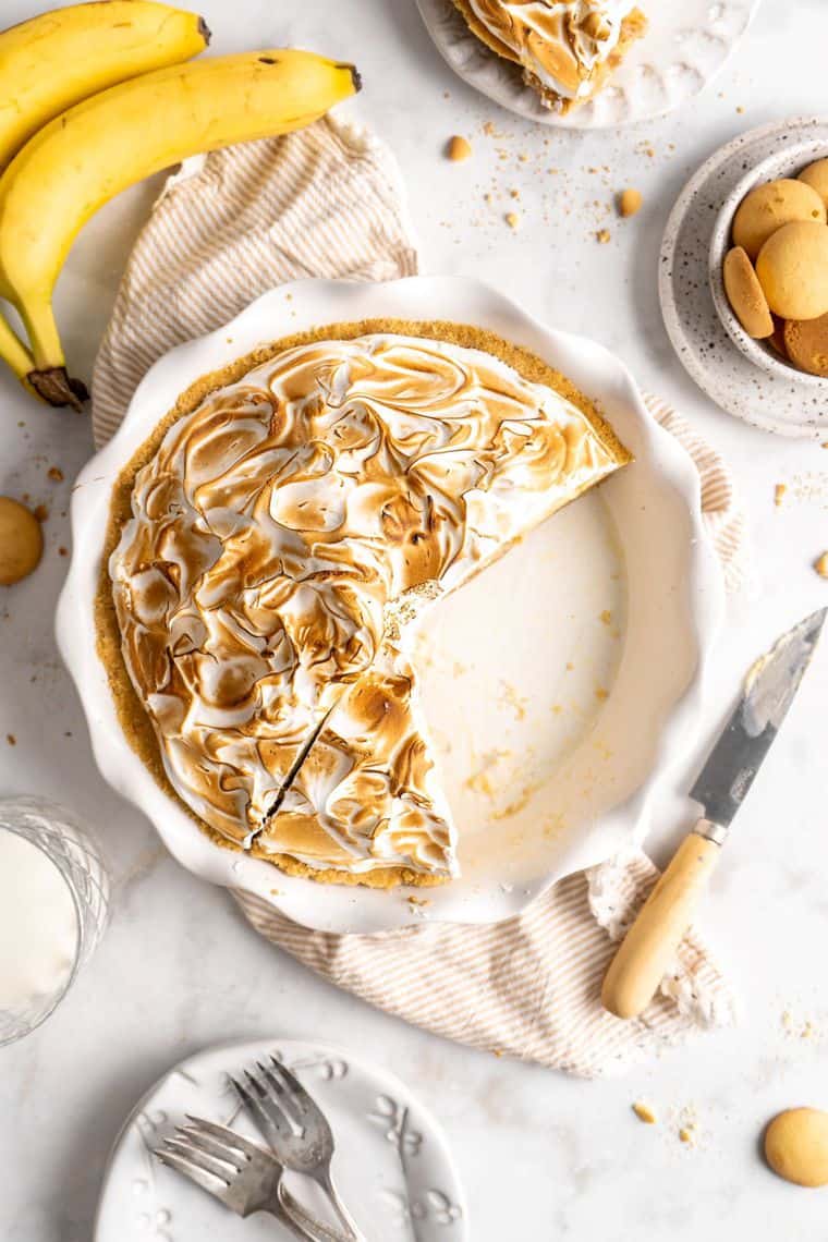 Banana cream pie with slices missing with bananas against white background