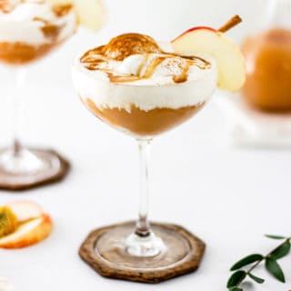 Two ice cream floats with caramel sauce and apple slices against white background