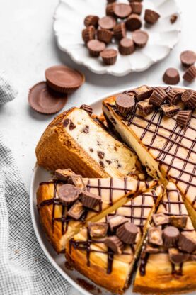 A delicious peanut butter and chocolate chip cheesecake with a slice ready to enjoy against white background