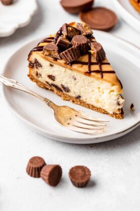 A slice of cheesecake with peanut butter and chocolate chips on a white plate
