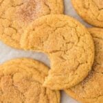 Snickerdoodle cookies with brown butter on parchment with a bite missing from one on top.