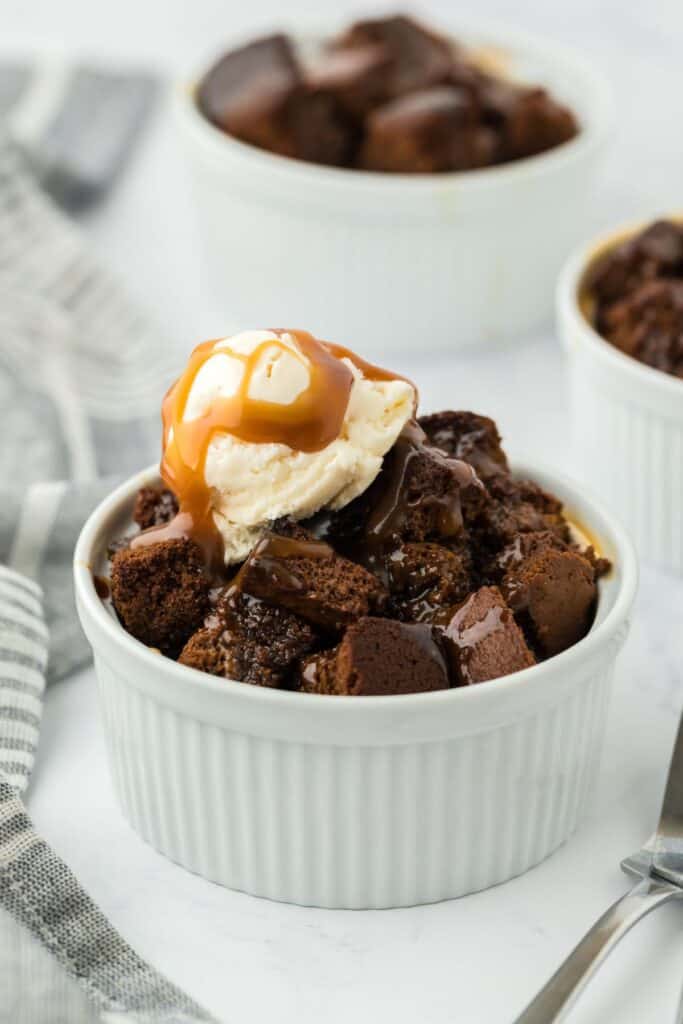 Gingerbread bread pudding in a ramekin topped with vanilla ice cream.