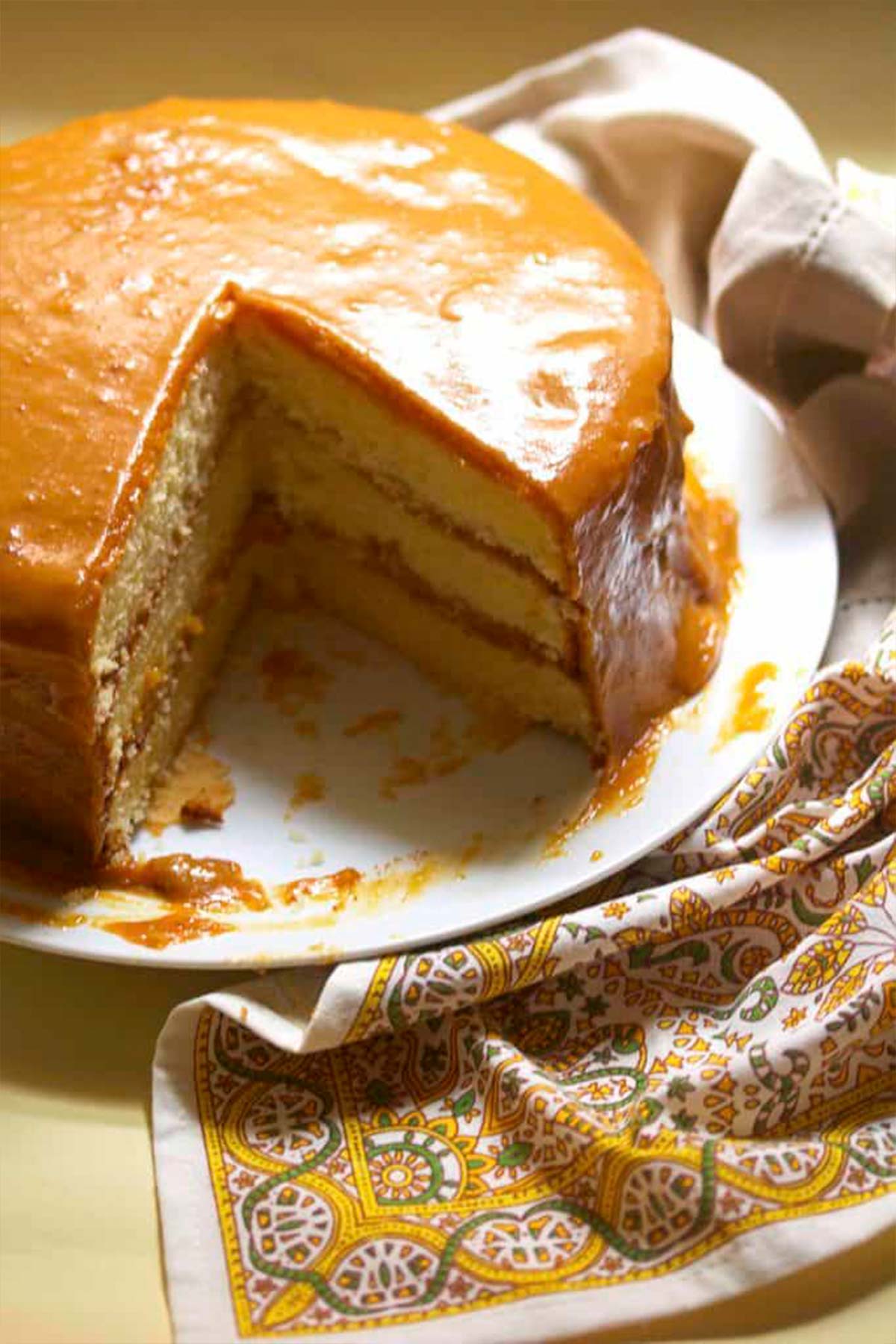 Caramel cake cut with a portion missing to show the inside of the cake.