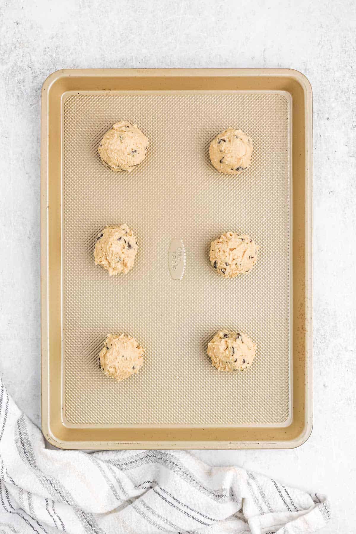 Mrs Fields cookie dough shaped into balls on a baking sheet.