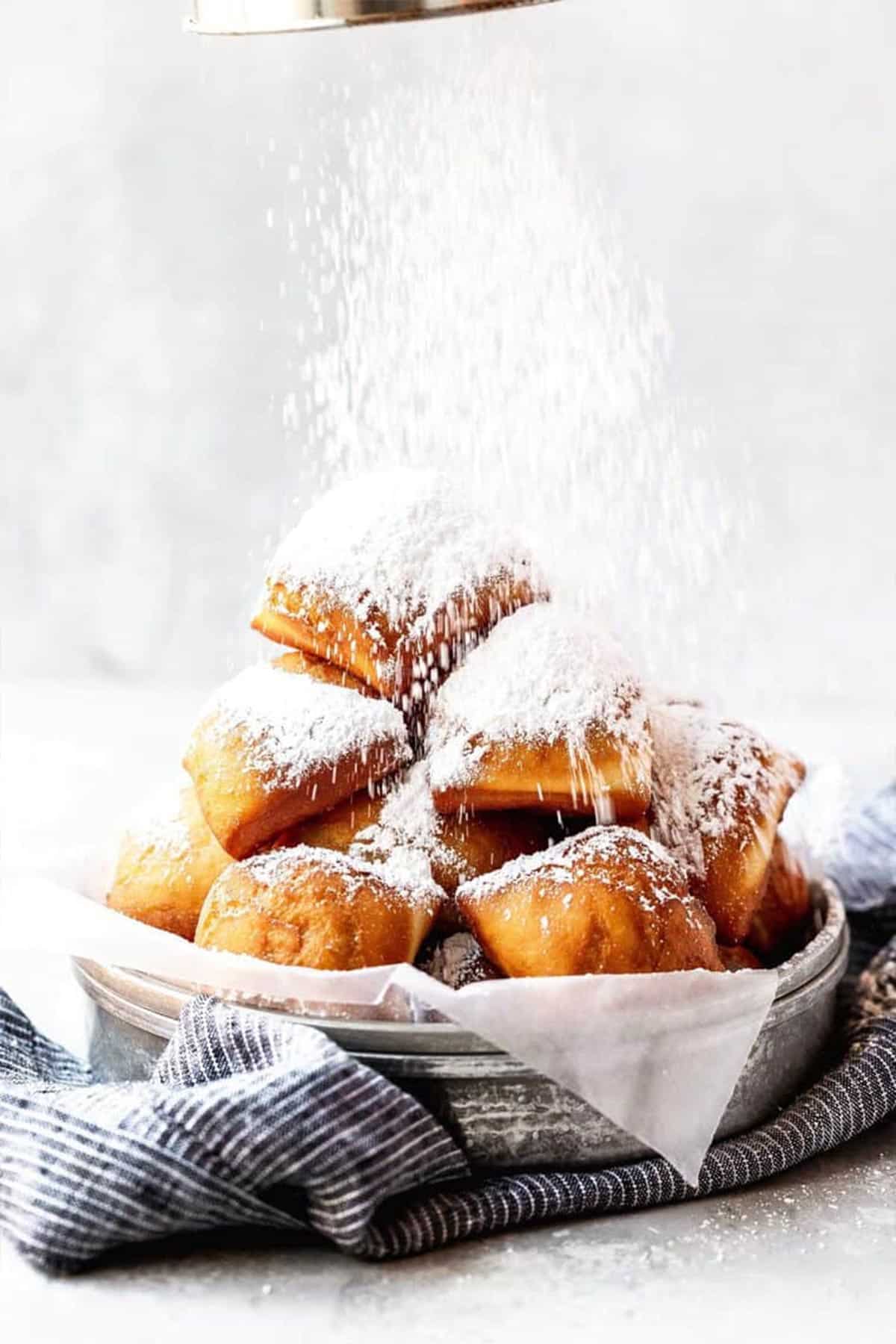 New Orleans beignets in a basket with powdered sugar sprinkled over top.