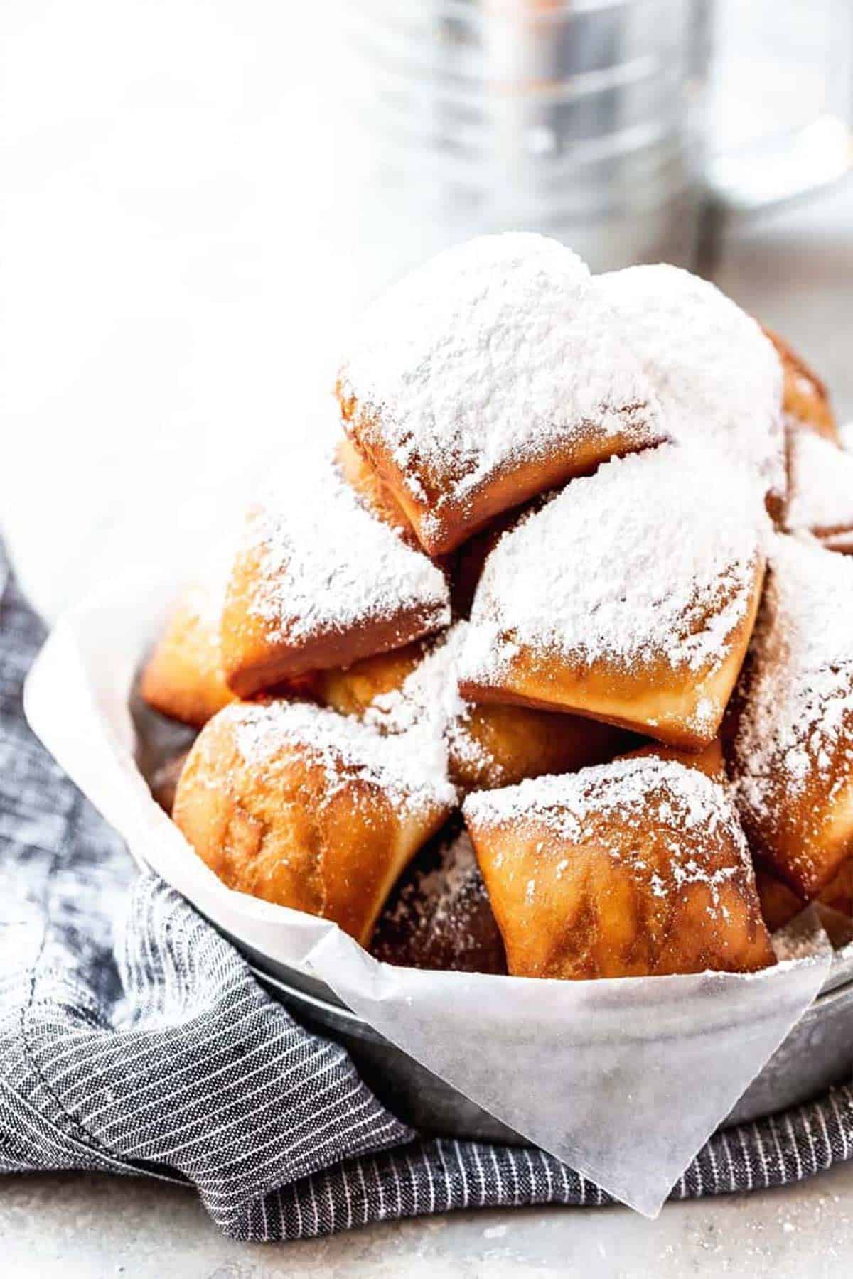 Close up of a bowl of beignets with powdered sugar.