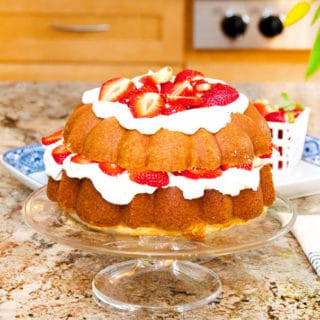 Strawberry pound shortcake sitting on a glass cake stand.