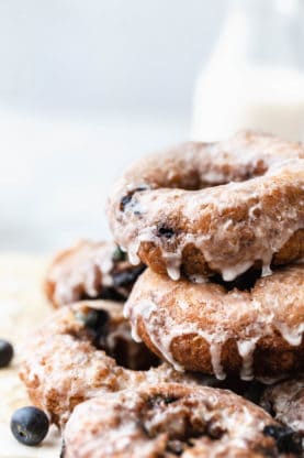 Close up of Stacked Blueberry Glazed Doughnuts and a bottle of milk in the background