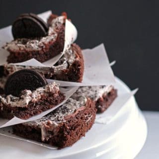 A stack of oreo cake bars placed on a white cake plate.