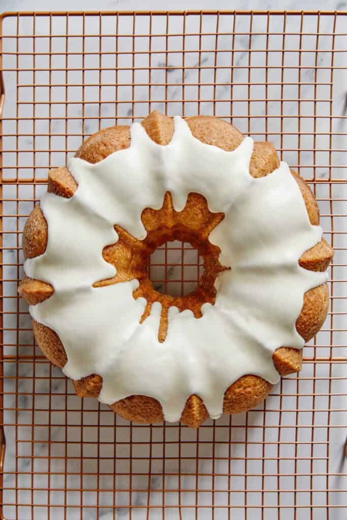 Overhead of cinnamon roll bundt cake on a wire rack with glaze poured over the top.