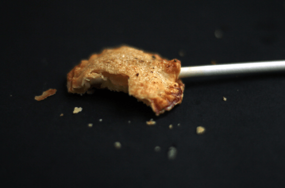 A half eaten creme brulee pie pop with a black background.