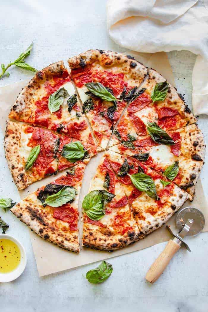 A close up of Neapolitan Pizza sliced with basil, cheese and marinara sauce ready to serve