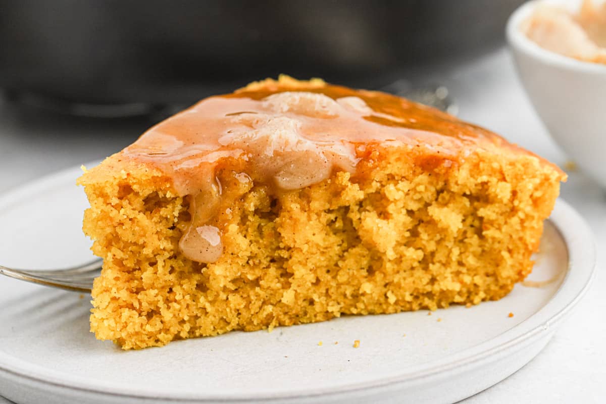 A slice of pumpkin cornbread topped with cinnamon butter on a plate.