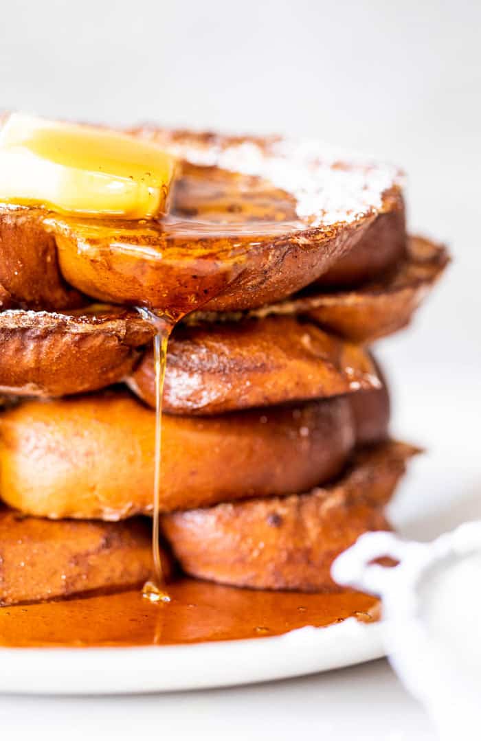 An extreme close up of fried eggnog french toast with butter and syrup melting down the top