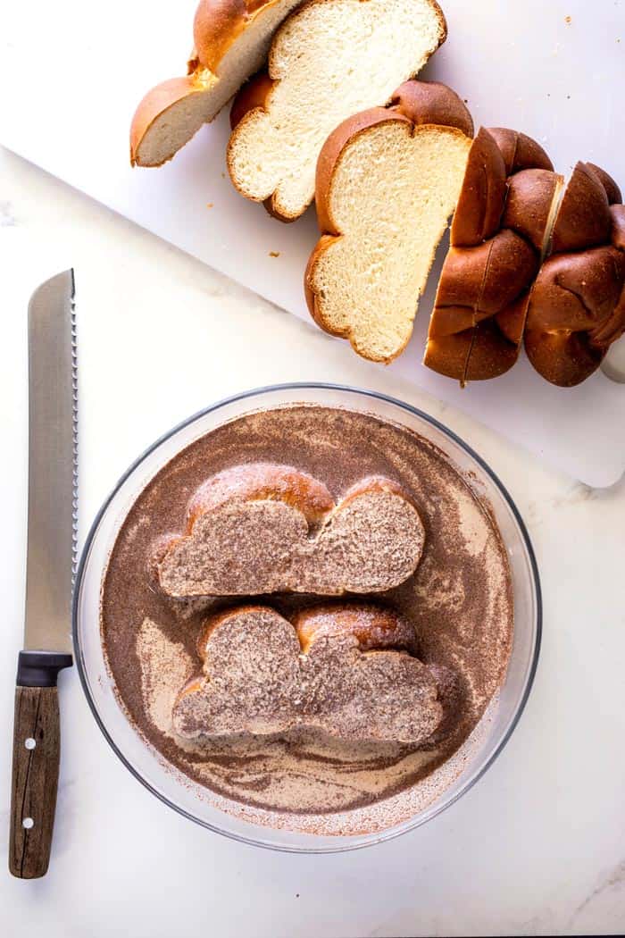 Two slices of challah dipped in eggnog custard next to sliced bread