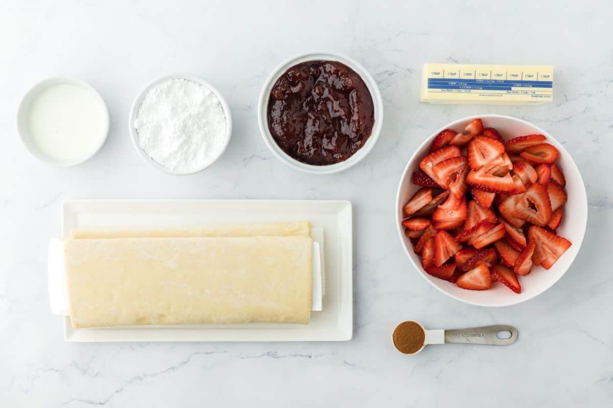 Ingredients to make strawberry cinnamon rolls with crescent rolls on the table.