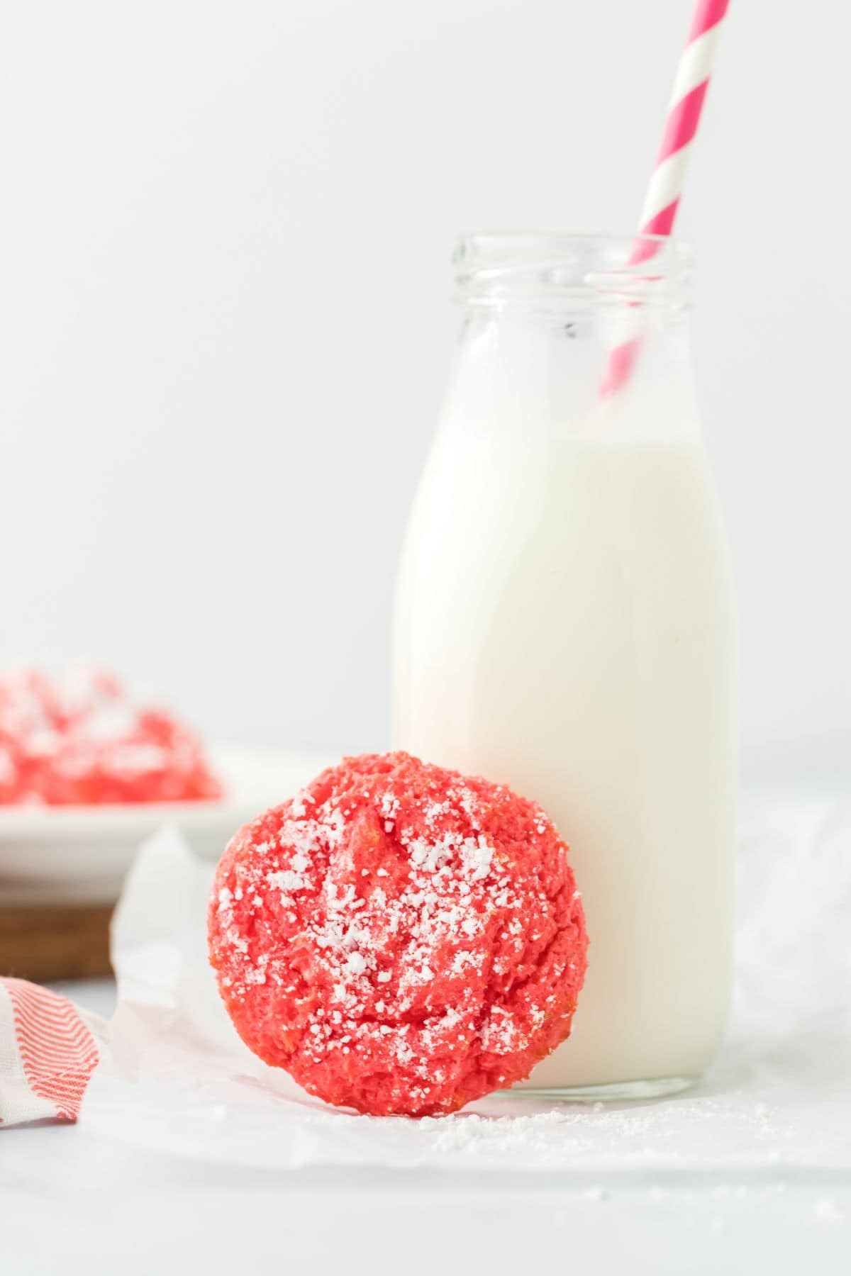 A raspberry gooey butter cookie leaning up against a bottle of milk.