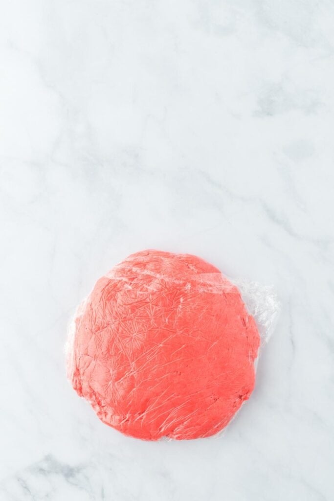 Raspberry gooey butter cookie dough wrapped in plastic wrap on countertop