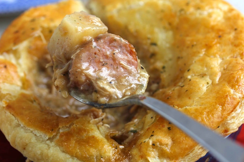 Extreme close up of a spoon holding a piece of sausage and potato from a creole pot pie