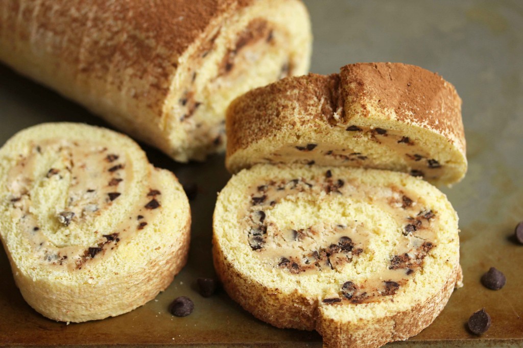 Cookie dough cake roll with three slices cut out and chocolate chips sprinkled around