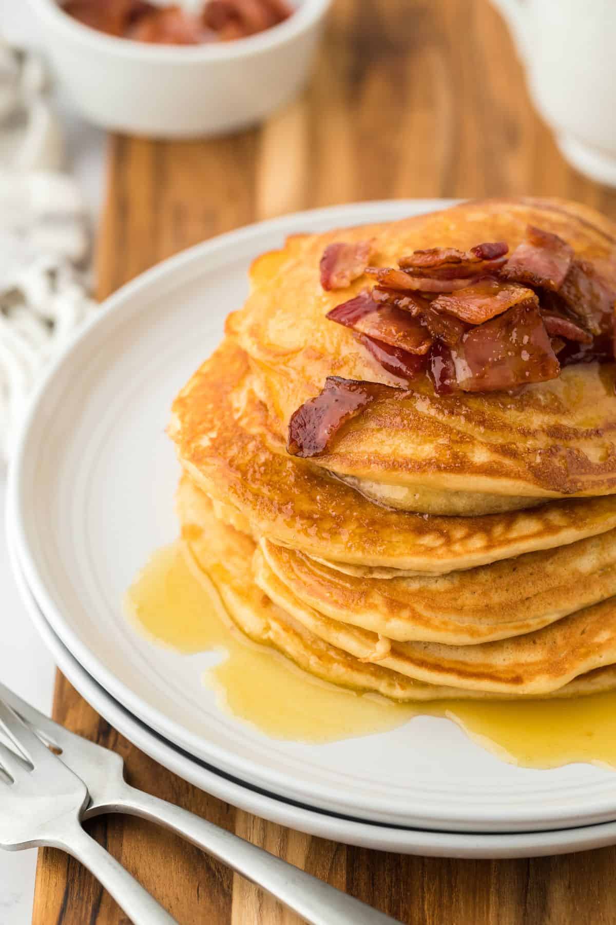 A stack of brown sugar pancakes on a plate with only half the plate in the image. 