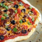 Mexican pizza topped with black olives, chorizo, chives and tomatoes
