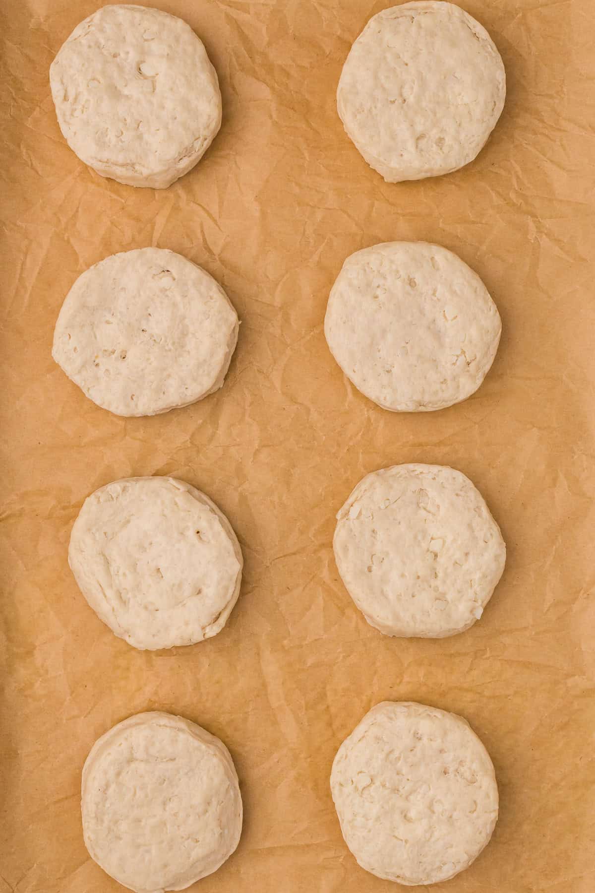 Raw biscuit dough rounds on parchment paper
