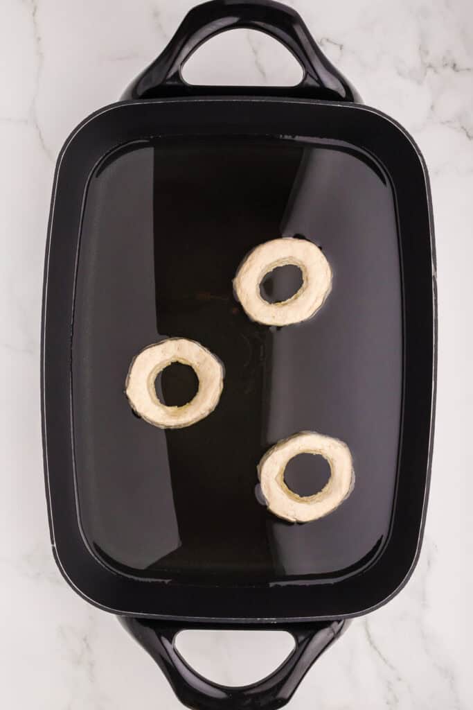 Doughnuts frying in a pan with oil