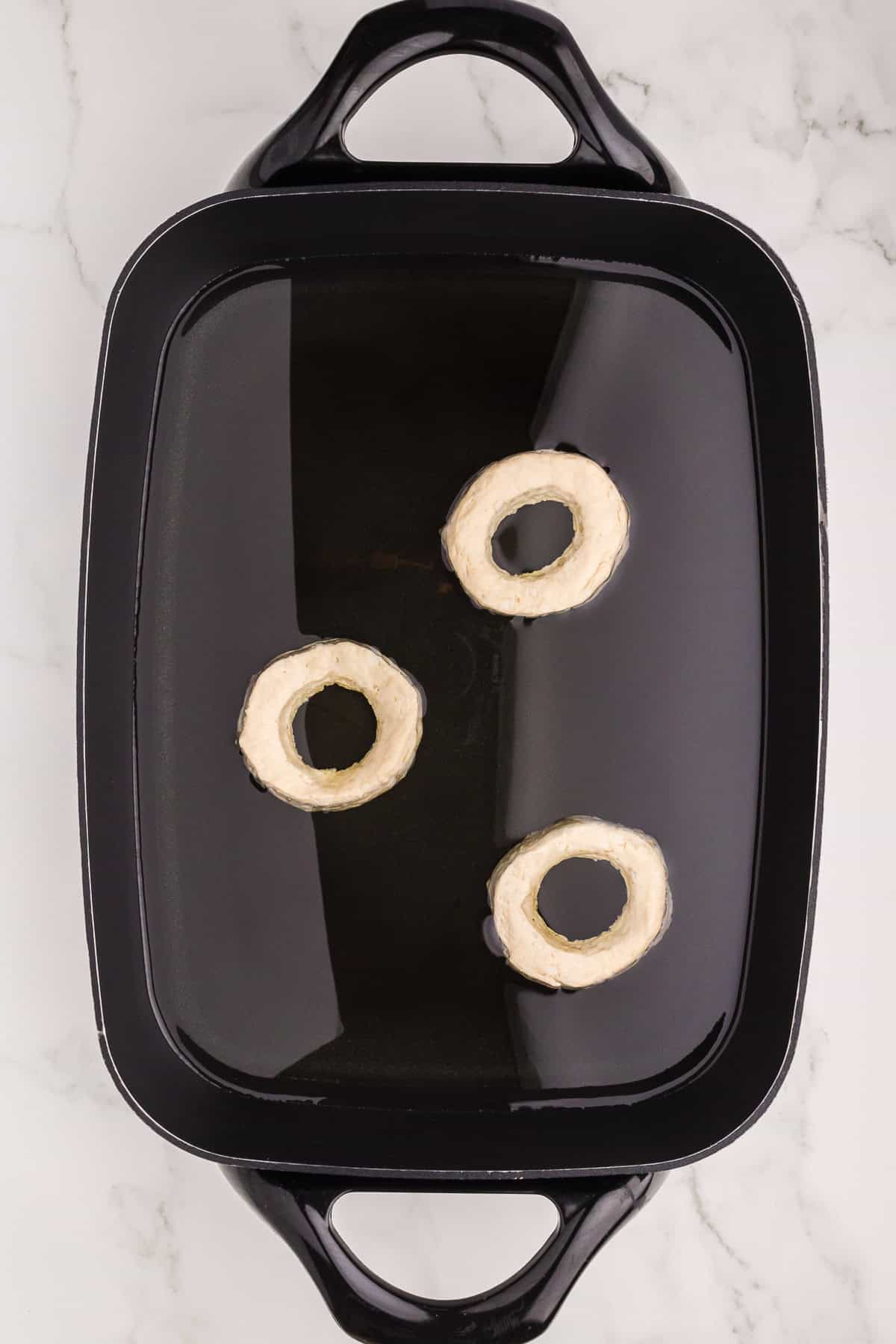 Doughnuts frying in a pan with oil