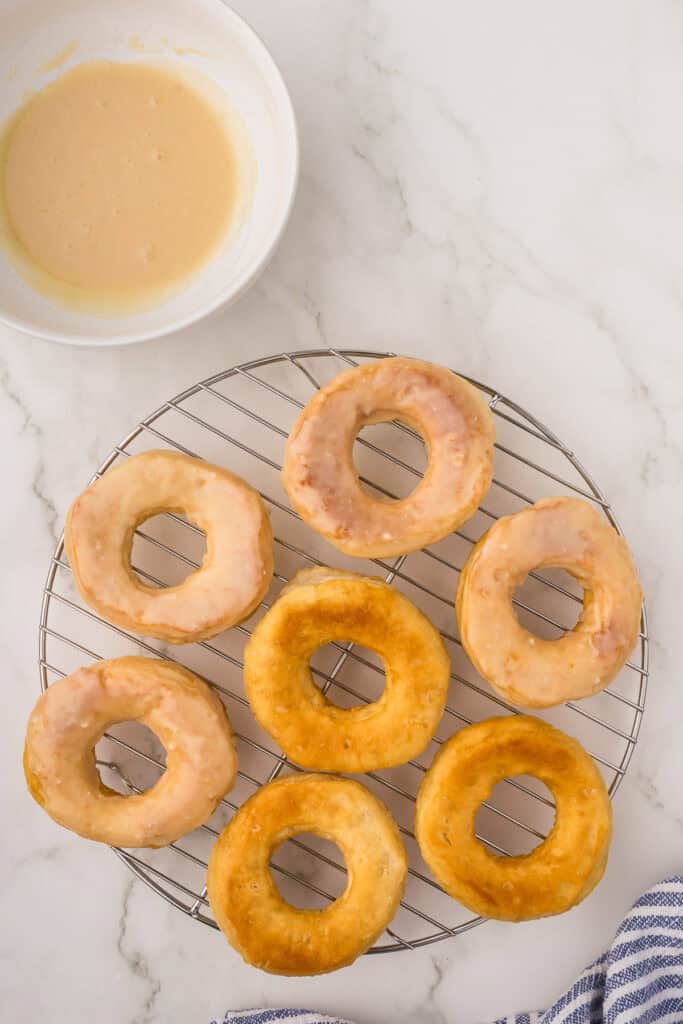 Several plain glazed doughnuts on a wired rack