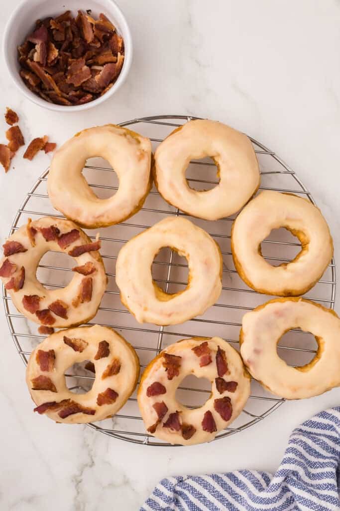Doughnuts topped with crispy bacon pieces on a wire rack