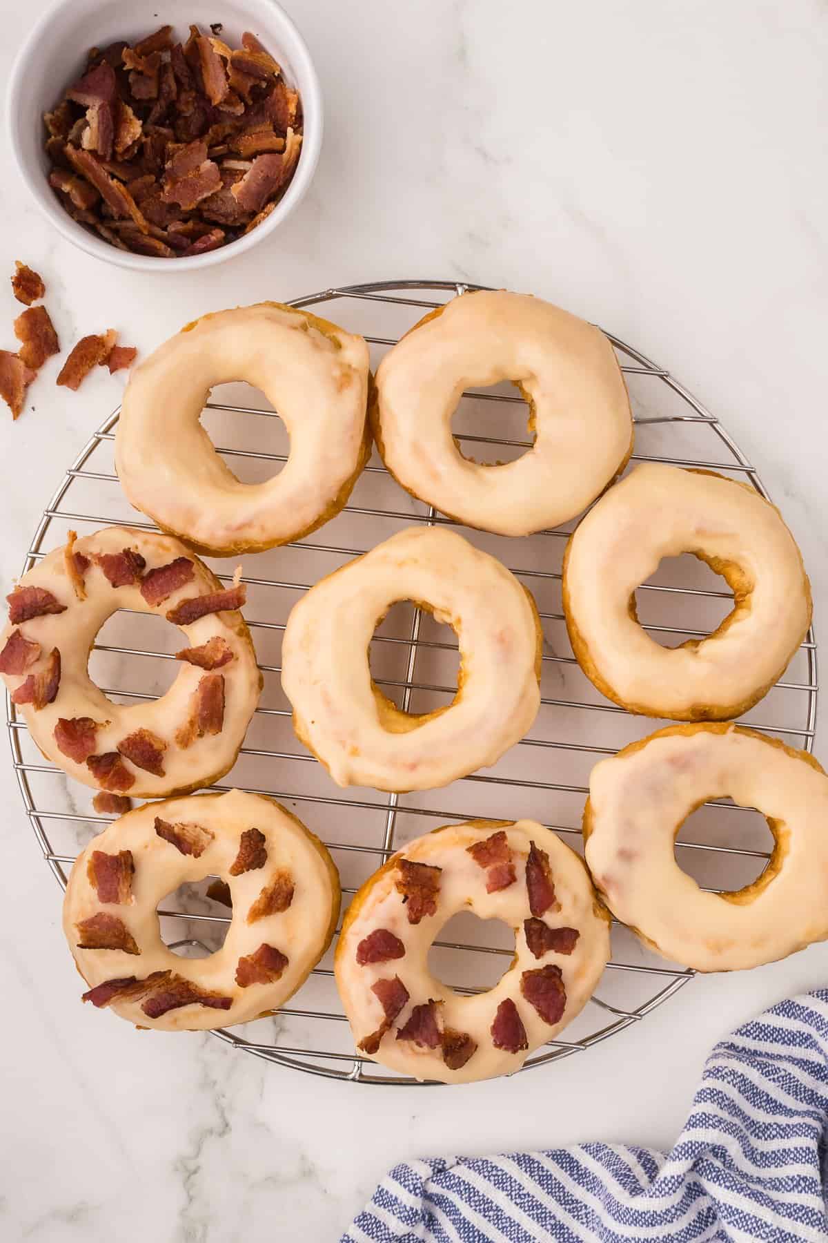 Doughnuts topped with crispy bacon pieces on a wire rack