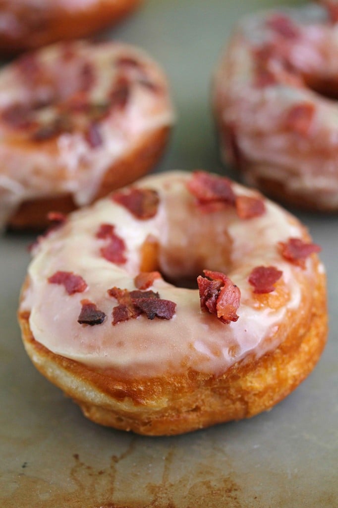 Close up of a maple bacon doughnut with more in the background and out of focus