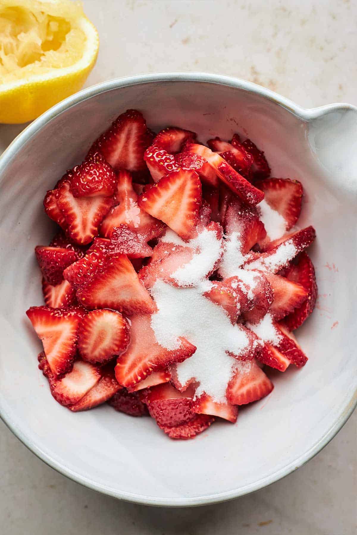 Strawberries in a bowl with sugar on top.