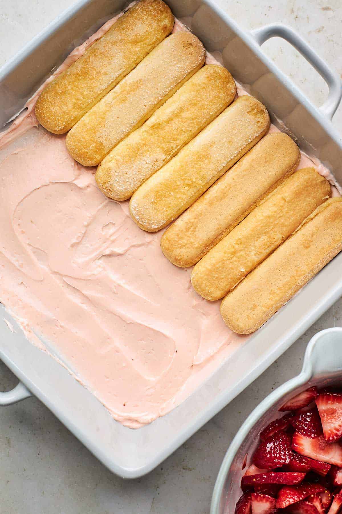 Strawberry cream in square pan with lady fingers on top.