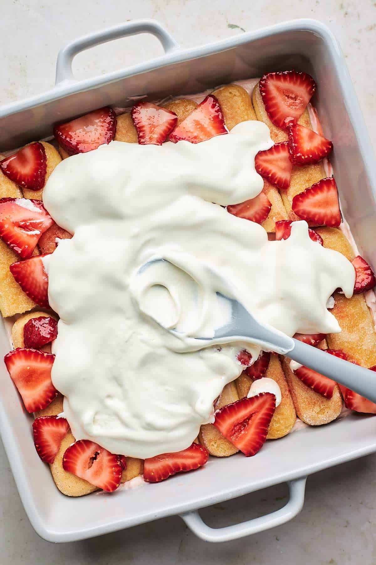 Whipped cream on top of the sliced strawberries.