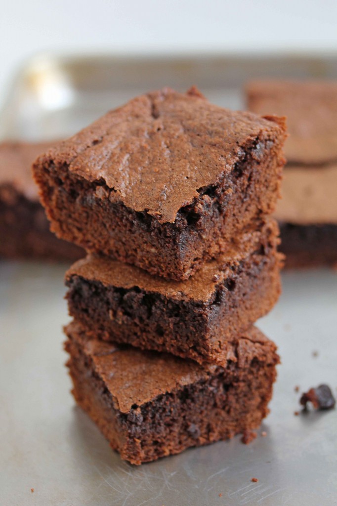 Three cakey brownies stacked on top of each other with more brownies in the background