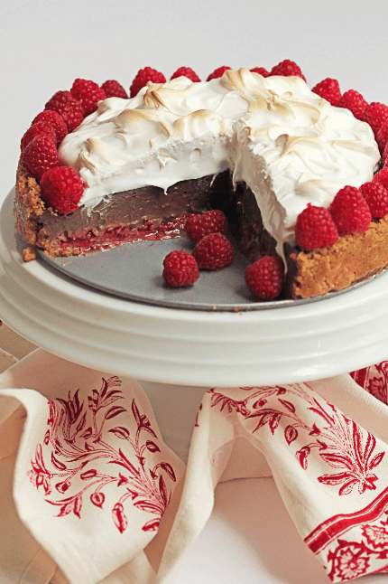 Raspberry s'more pie with slices missing sitting on a white cake stand