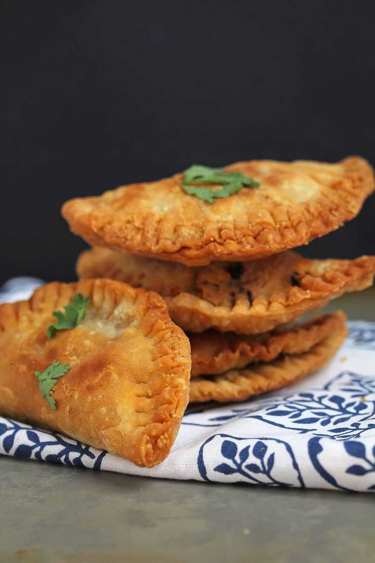 Close up of a stack of Ground Turkey Empanadas sitting on a white and blue cloth on a black background