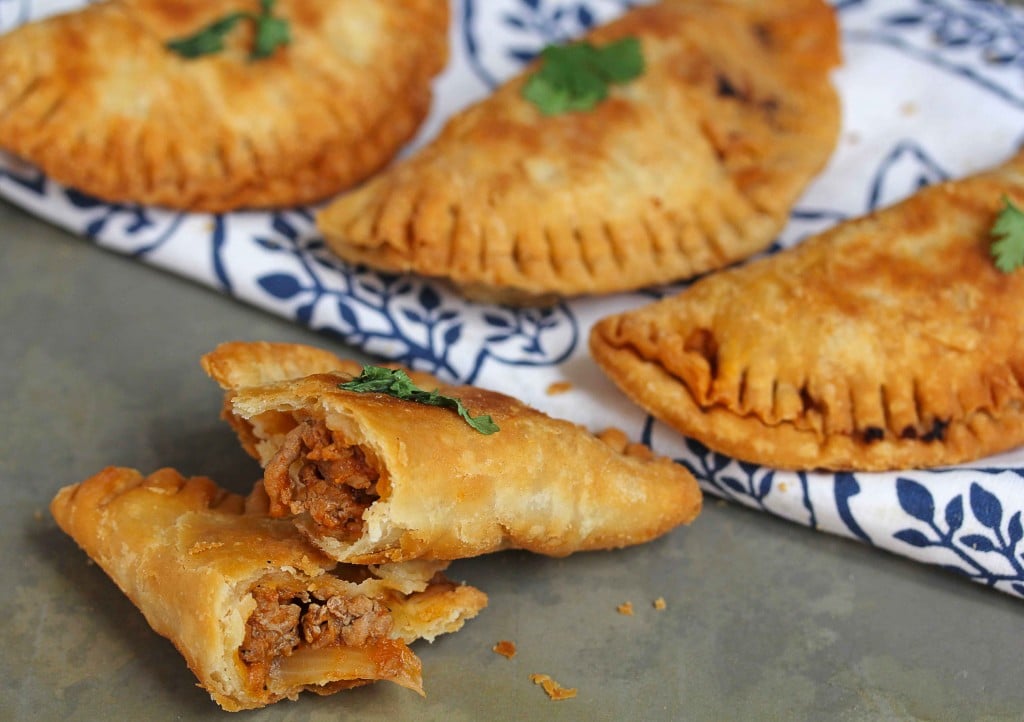 A ground turkey empanada cut in half with three more in the background