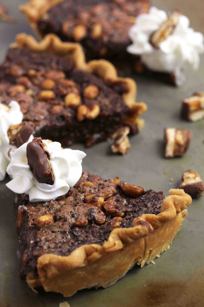Three slices of fudge pie with pieces of candy bars scattered around them