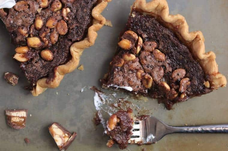 Overhead shot of two slices of fudge pie with a fork and pieces of candy bar scattered around