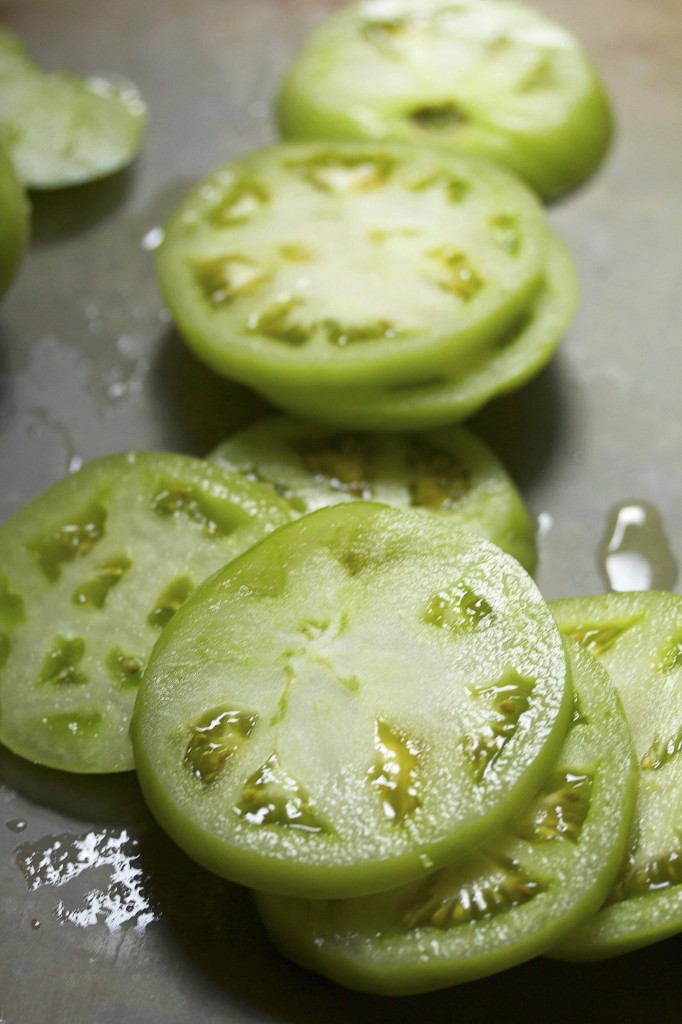Close up of several sliced green tomatoes ready to be fried to golden perfection