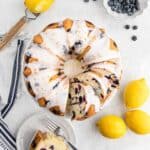 Overhead shot of lemon blueberry pound cake with glaze, sliced on a plate with fresh lemons and blueberries
