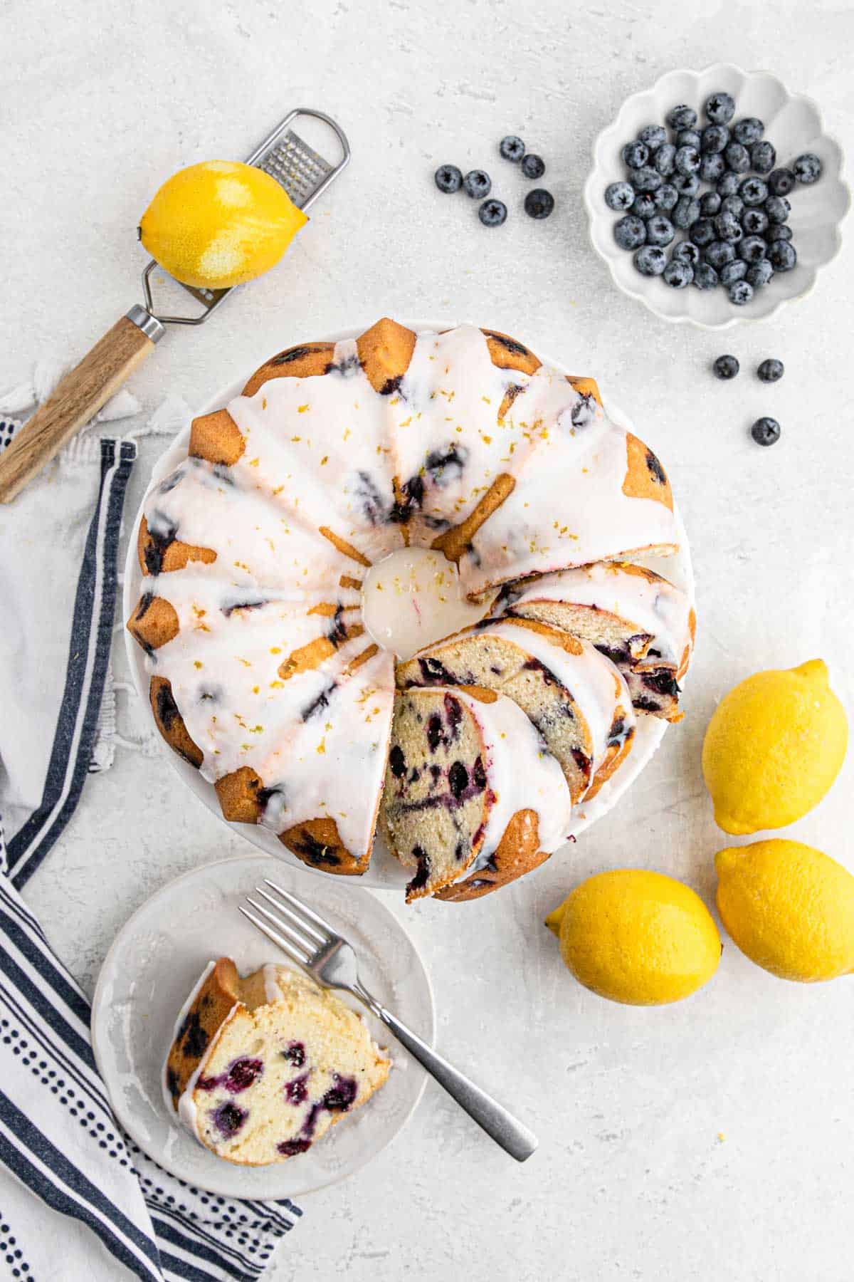 Blueberry Lemon Pound Cake with slices cut on a white background with lemons and blueberries around