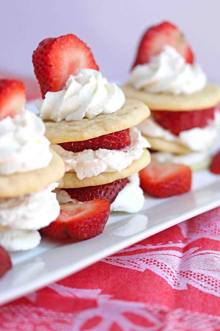 Close up of succulent strawberry slices sandwiched between fresh whipped cream and moist, chewy tea cakes.