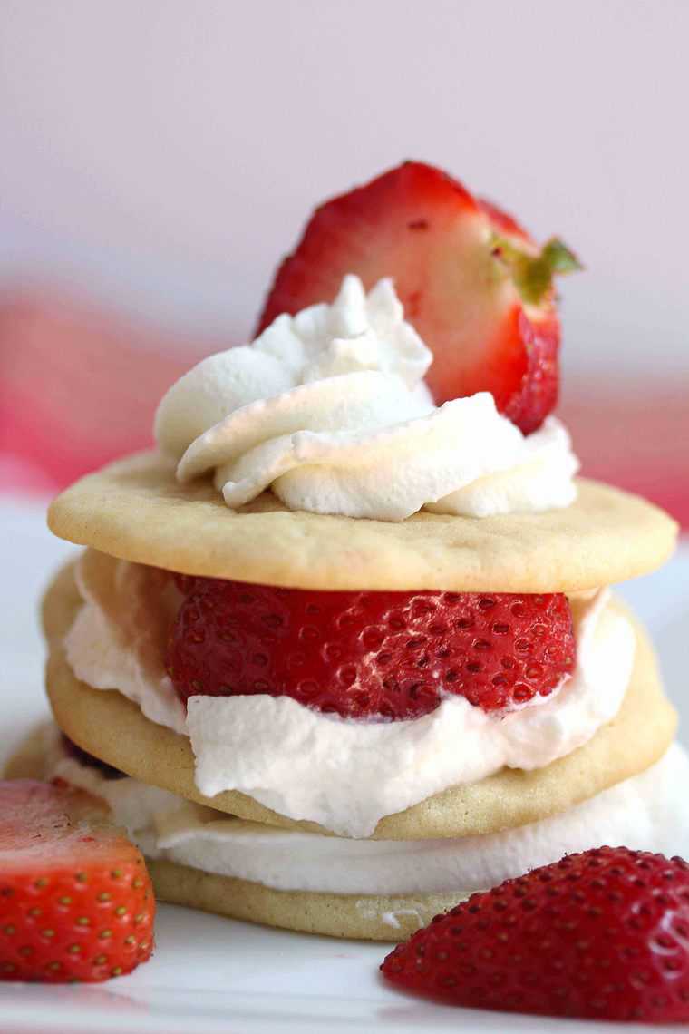 Close up of one strawberry shortcake tea cake stack with sliced strawberries in the foreground