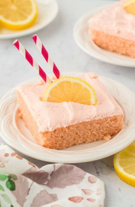 a square slice of pink lemonade cake topped with a lemon.