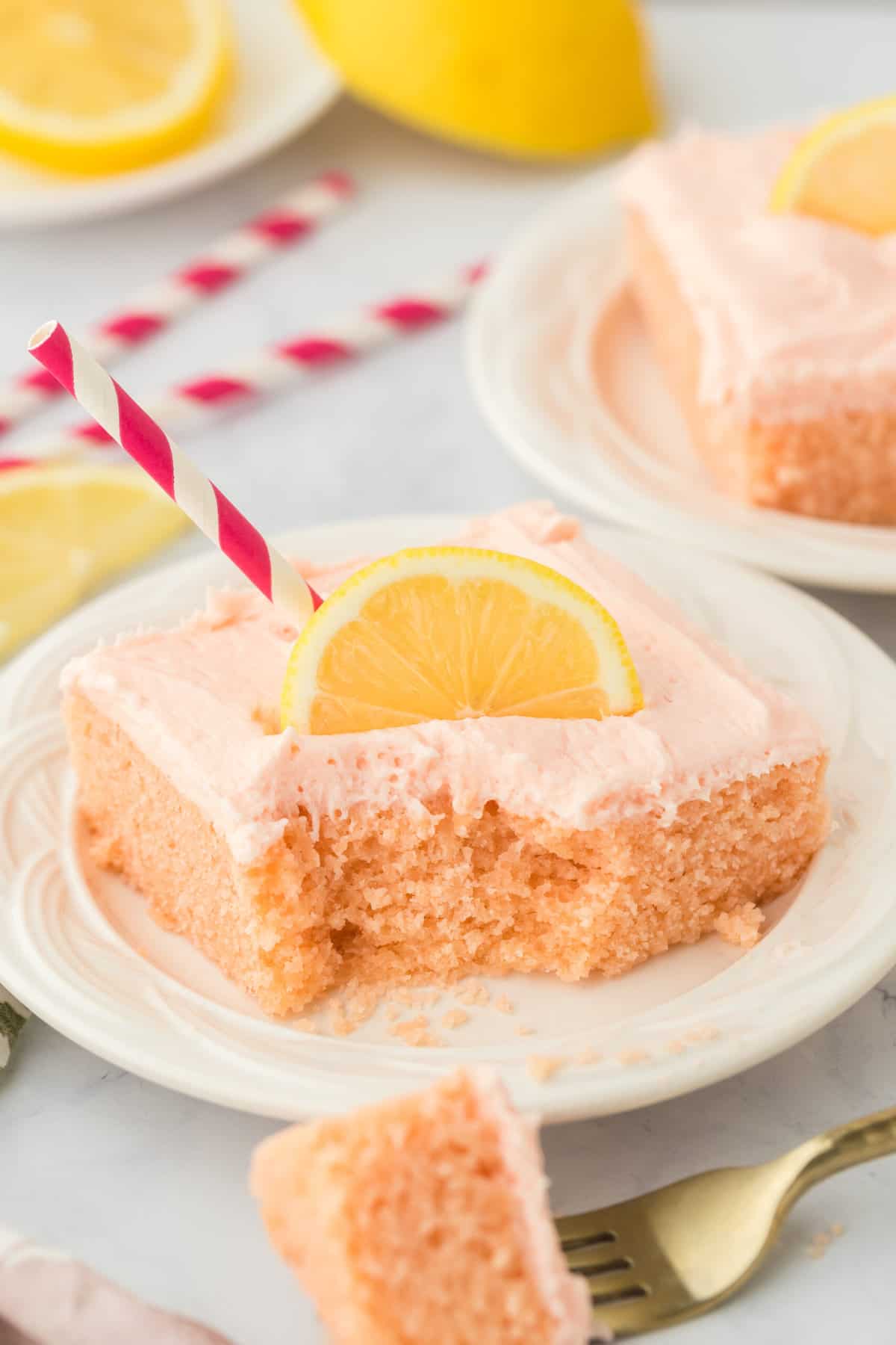 a square slice of pink lemonade cake topped with a lemon.