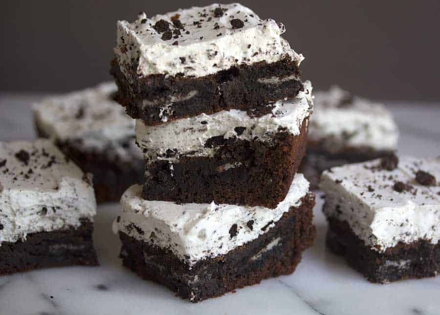 Three cookies and cream brownies stacked on top of each other with other brownies surrounding them
